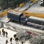 Farmers fight: Police work force stand watch close to a boundary and vehicles impeding a street to forestall farmers fighting to request least harvest costs from walking towards India's capital at the Delhi-Uttar Pradesh line in Ghazipur.